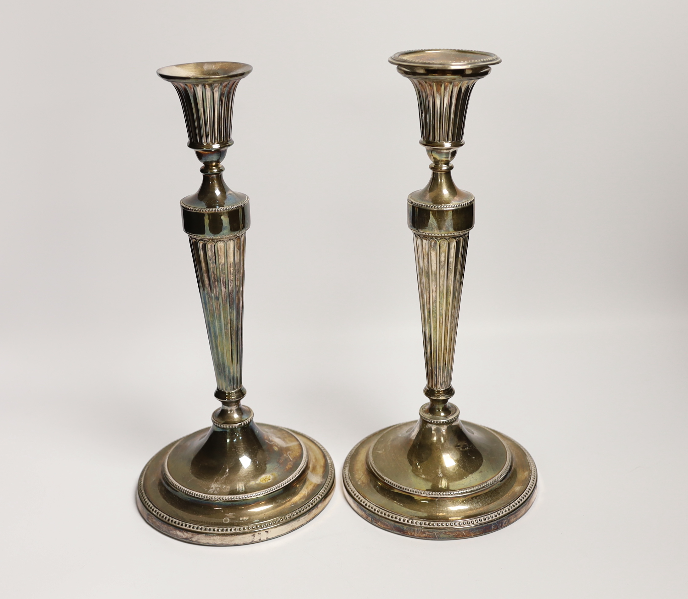 A pair of George III silver candlesticks, with waisted fluted stems, John Winter & Co, Sheffield, date letter rubbed, circa 1780, height 30cm, weighted, lacking one sconce.